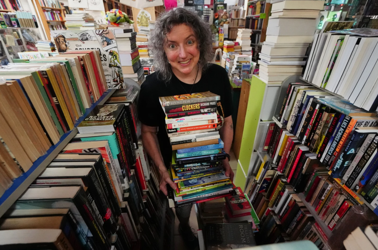 Michelle Souliere, owner of the Green Hand Bookstore, carries a stack of books to the shelves in Portland, Maine on Aug. 7, 2025.AP 