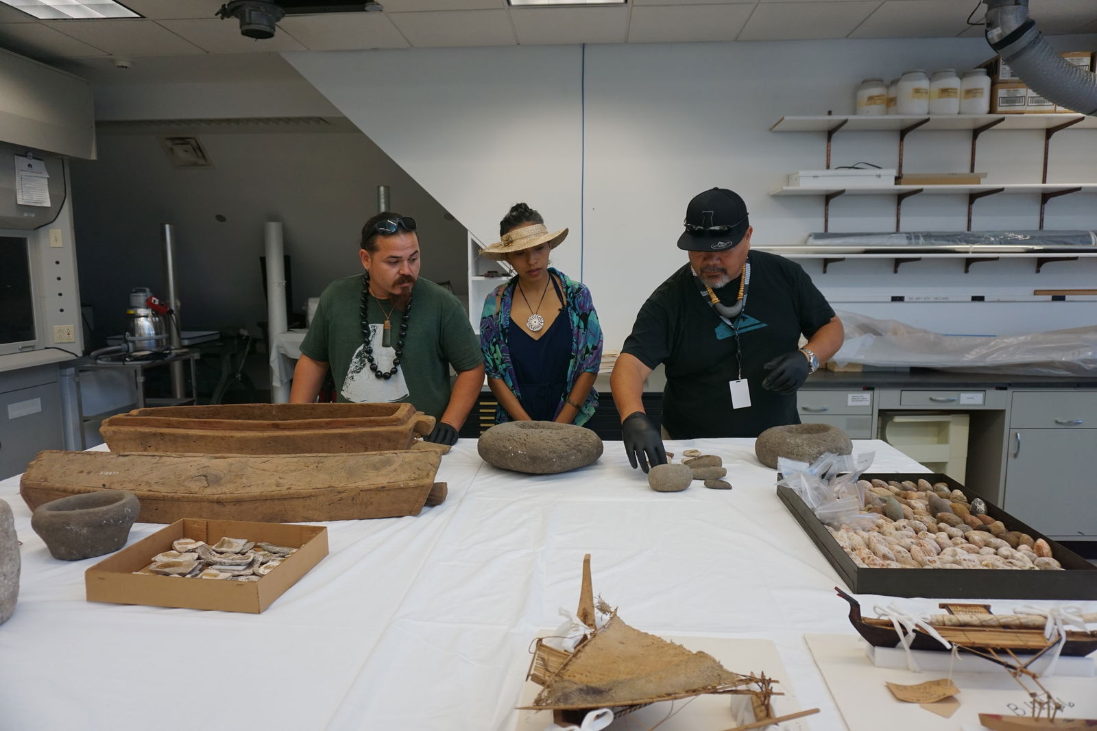 Tyler Warwick, Eva Cruz, and Martin Naputi examine Marianas artifacts that are part of the Hornbostel Collection.