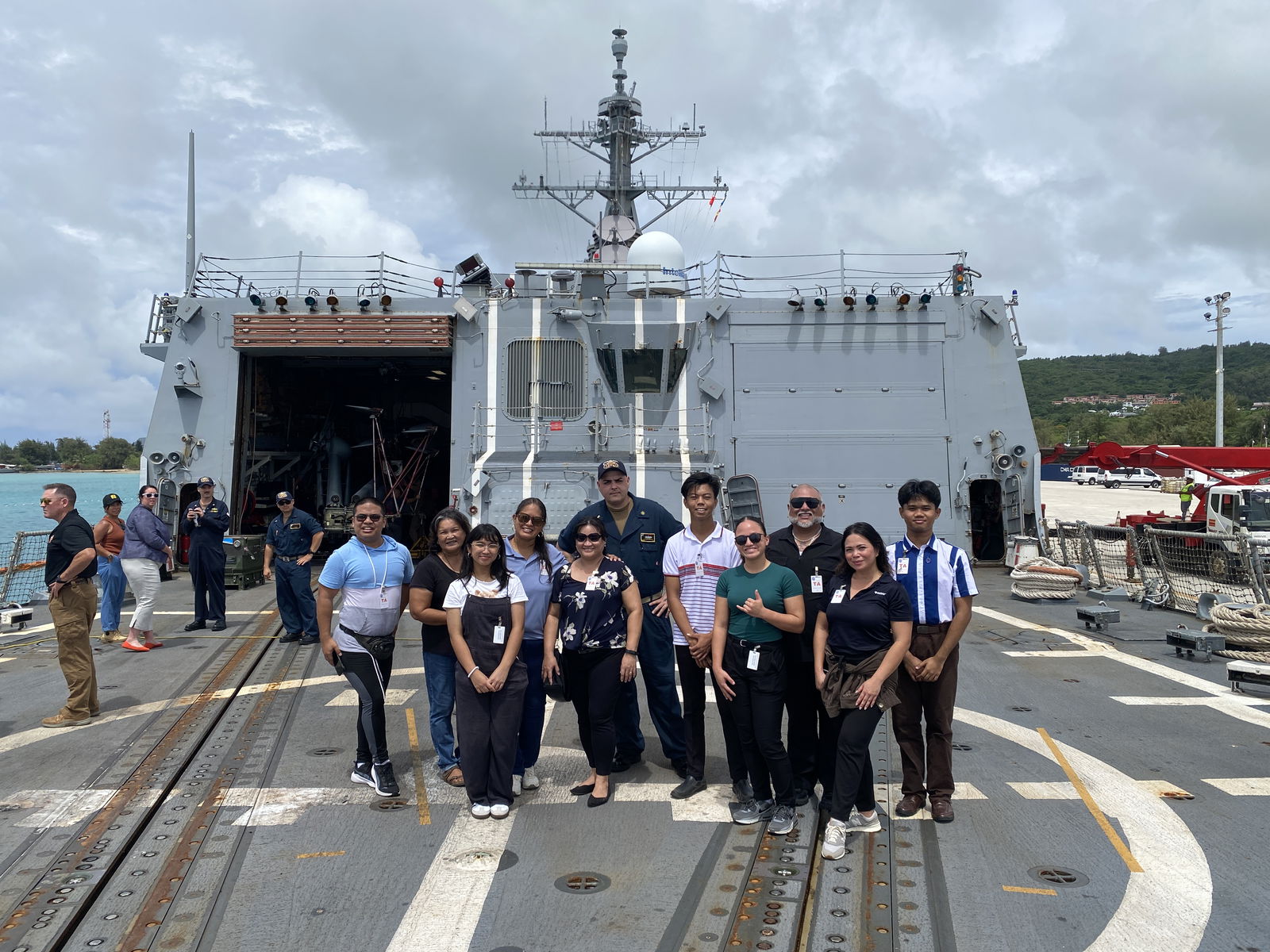Residents who are part of the tour pose for a photo on the helicopter landing pad aboard the USS Shoup.