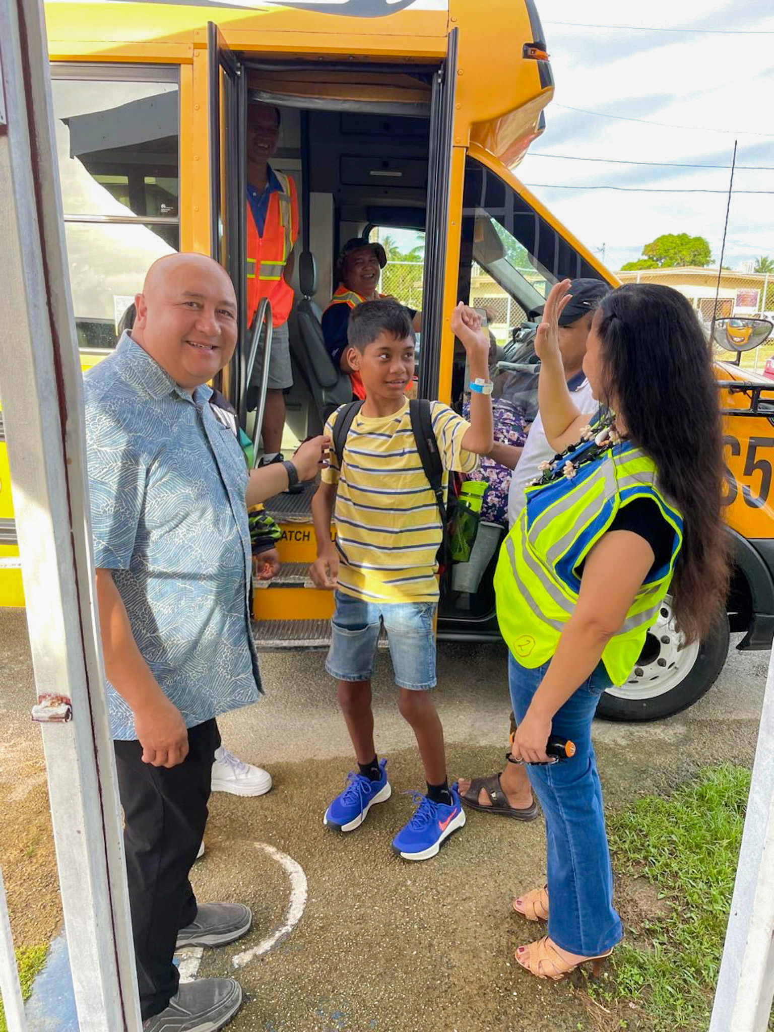 Commissioner of Education Dr. Lawrence F. Camacho and Tanapag Middle School Principal Hilda Rios welcome students as they step off a school bus.