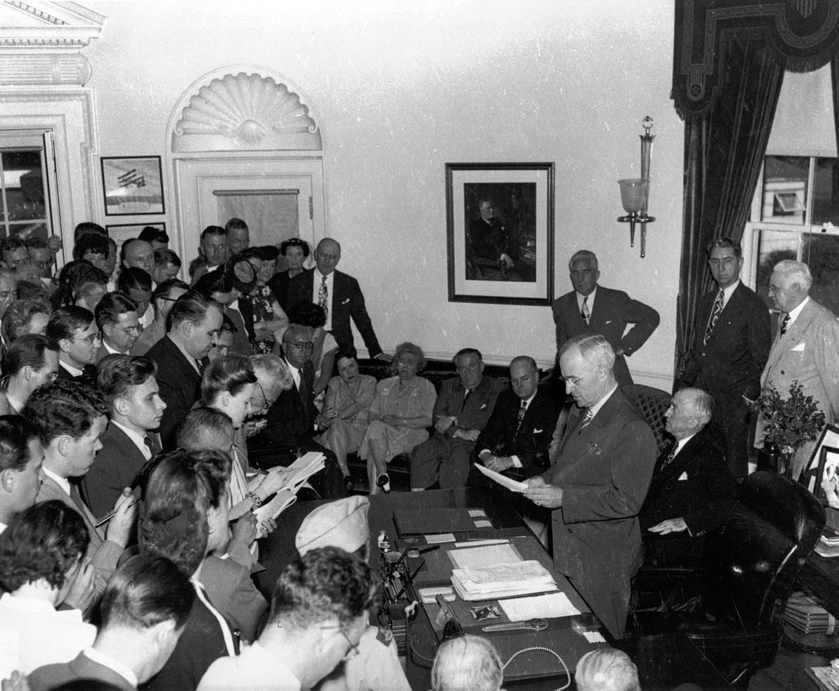 President Harry Truman announces the surrender of Japan to the media in the Oval Office.