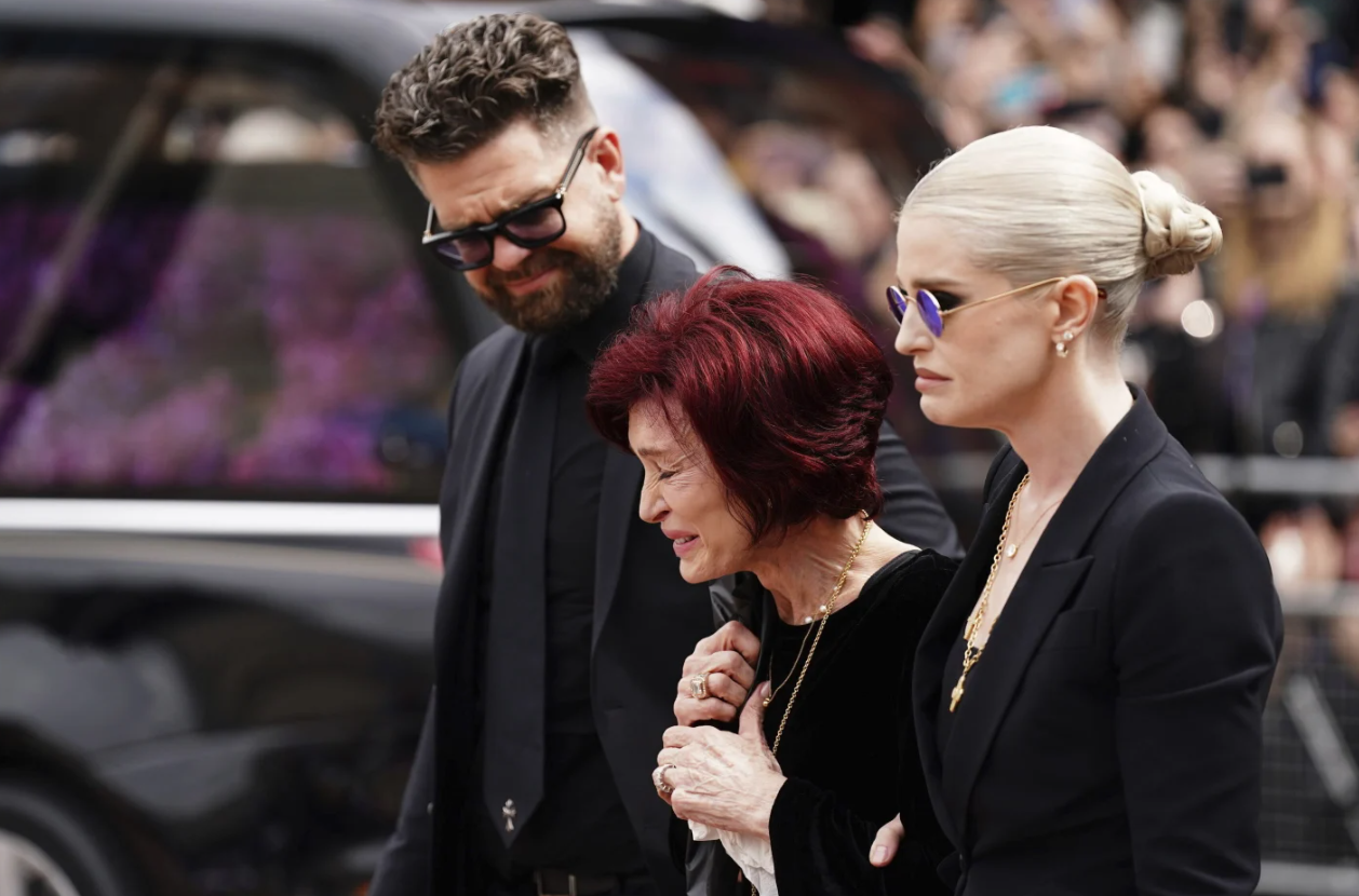 The family of Ozzy Osbourne from left, Jack Osbourne, Sharon Osbourne and Kelly Osbourne lay flowers and view the flowers left at the Black Sabbath Bridge bench on Broad Street in memory of Black Sabbath frontman Ozzy Osbourne ahead of the funeral procession, in Birmingham, England, Wednesday July 30, 2025.AP