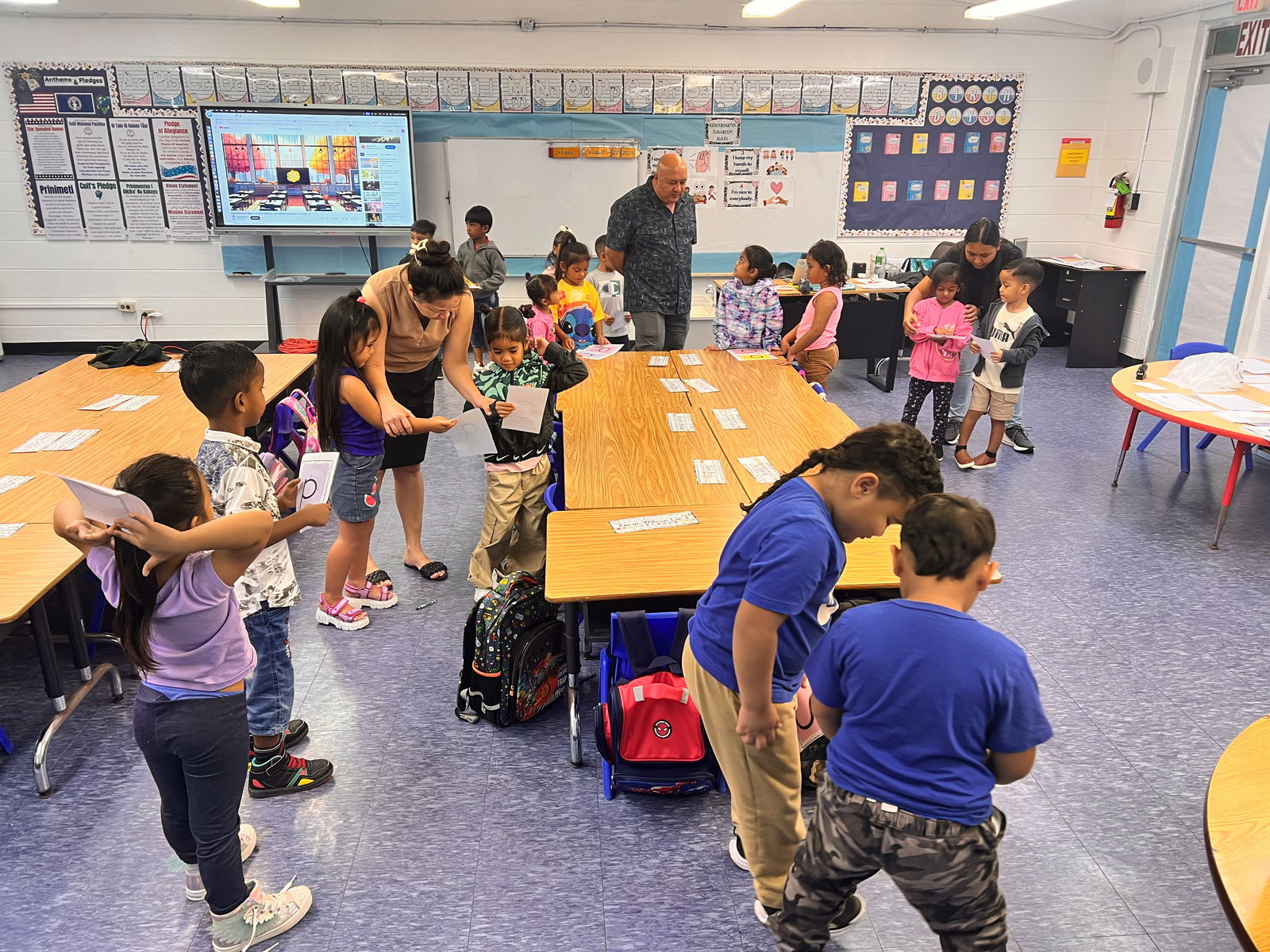 Kindergarten students at Tinian Elementary School practice writing uppercase letters on the third day of the new school year, Aug. 19. The Public School System blends technology-based tools with traditional methods to maximize learning. In the background, Commissioner of Education Dr. Lawrence F. Camacho visits the classroom as part of his tour of all 20 campuses across Saipan, Tinian, and Rota, engaging directly with teachers, staff, and other public school stakeholders. 