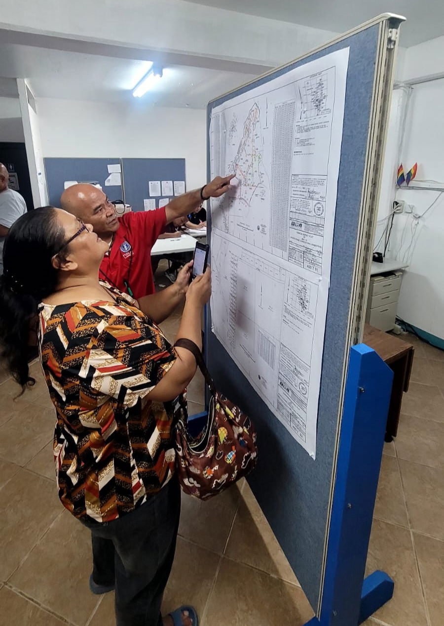 Assisted by DPL staff member Anthony Tomokane, a Tinian resident looks at the lots drawn on map.
