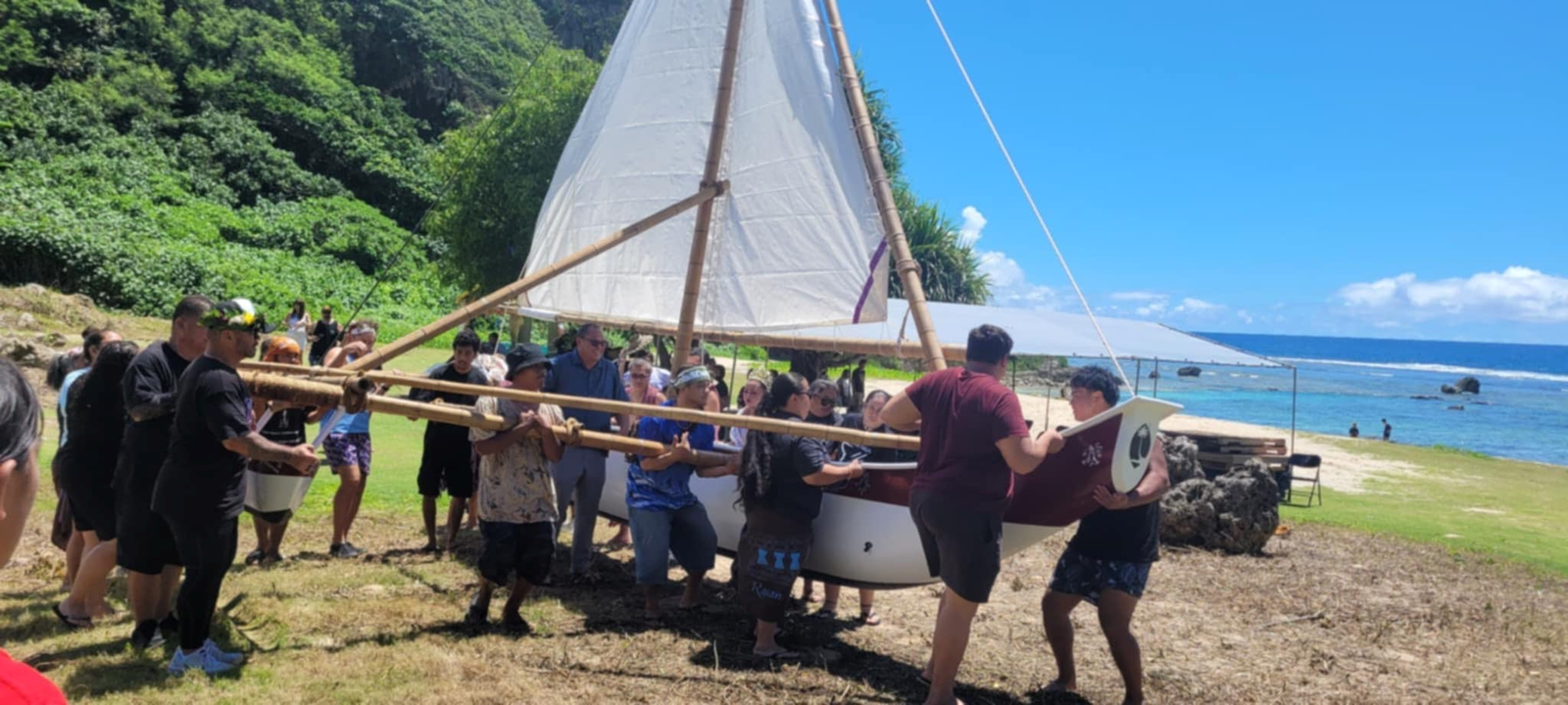Guam residents carry the new canoe to the waters of Tagachang Beach on Saturday, Aug. 2.