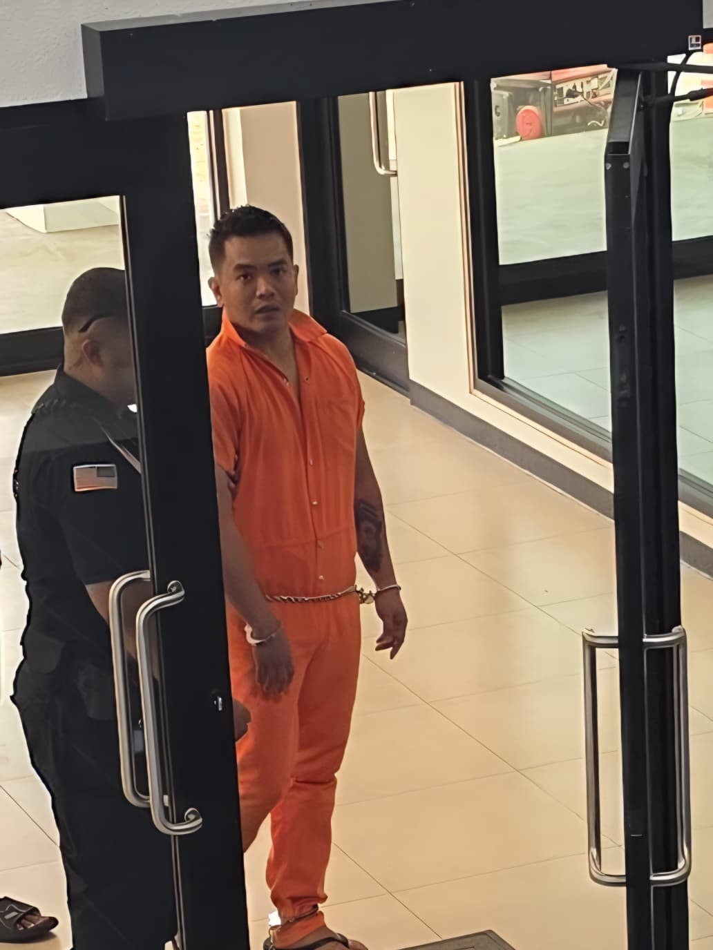 Gerald Serrano enters the Guma Hustisia escorted by a Corrections officer on Tuesday.