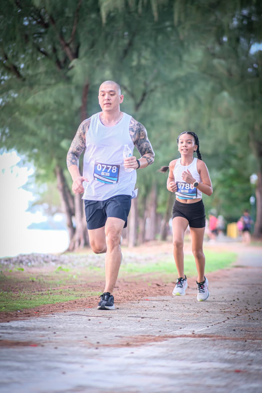 Brooklyn Jones, with her father, leads the U12 girls division of the Run Saipan inaugural ASC Trust 401K Day Sunset Strides 5K on Beach Road in Garapan on Friday.